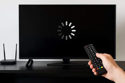 Smart TV showing a buffering spinner with a remote in hand