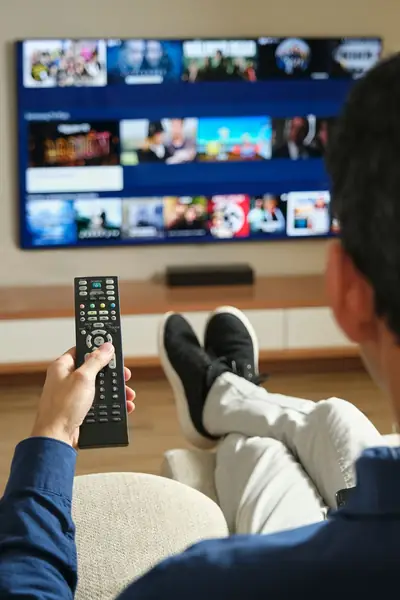 Person browsing a streaming library on a TV with a remote
